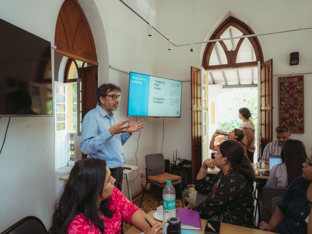 A presenter speaking to participants seated around tables